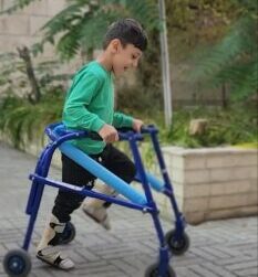 تمرین راه رفتن کودک با واکر چرخدار در برنامه توانبخشی در منزل